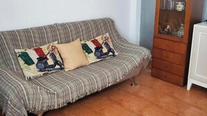 A living room with a sofa, a cabinet, and two framed pictures on the wall. - Nice Apartment in Natura World, Almeria (Vera)