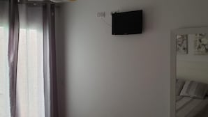 A room with a bed, a flat-screen TV mounted on the wall, and a window with curtains. - Nice Apartment in Natura World, Almeria (Vera)