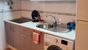 A compact kitchen with a built-in washing machine, a sink, and a stove. - Nice Apartment in Natura World, Almeria (Vera)