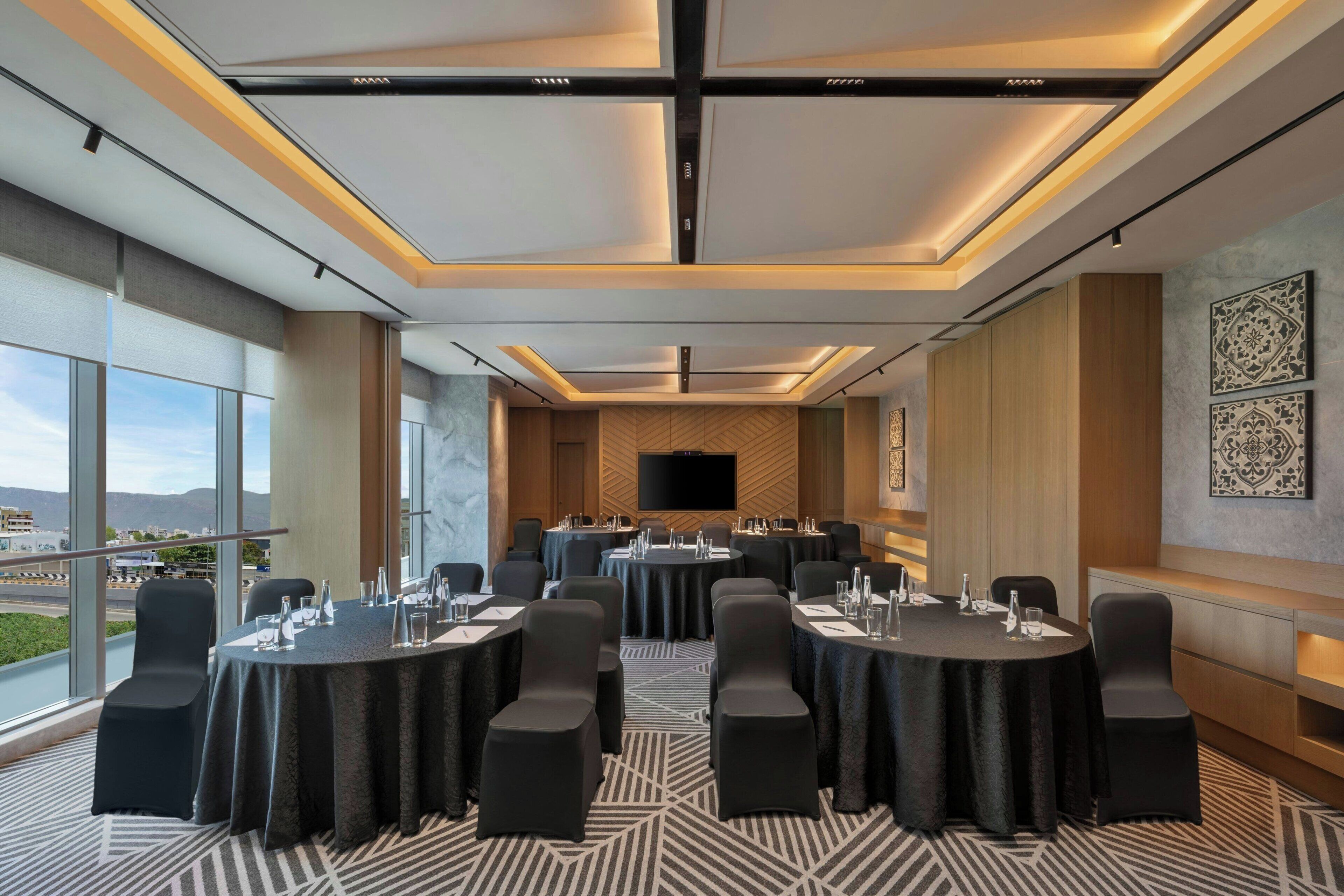 A conference room with round tables, chairs, and a large screen.