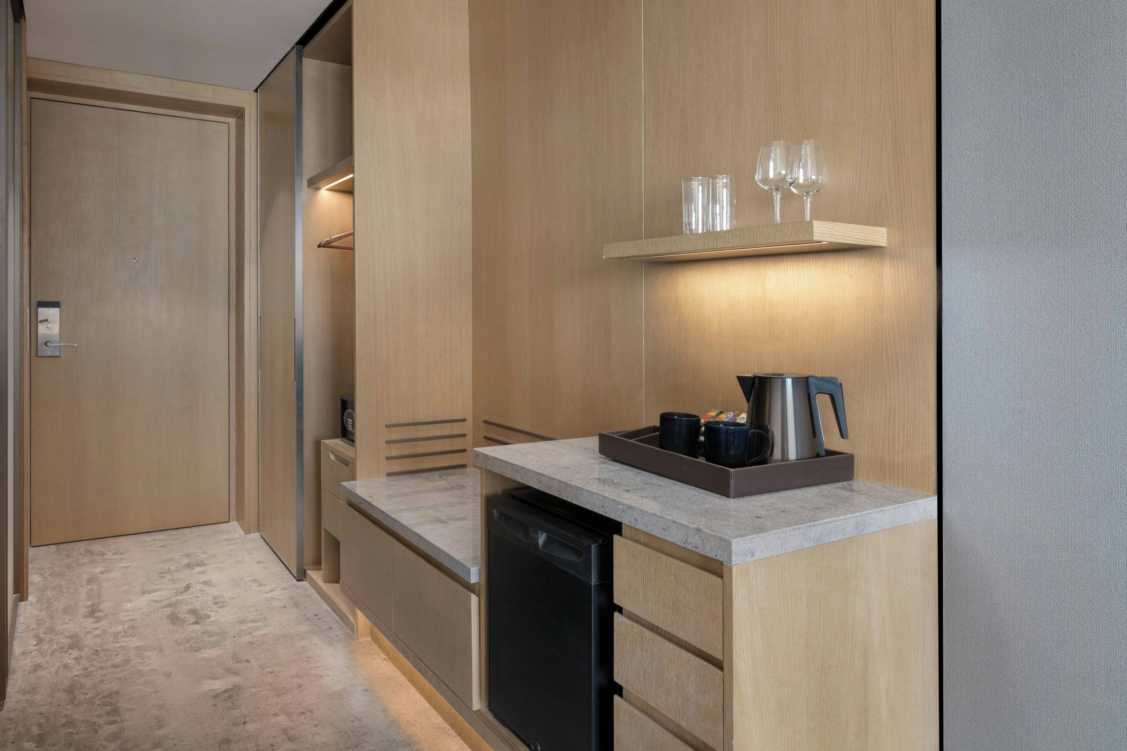 Eine moderne Küche mit eingebautem Geschirrspüler, einer Arbeitsplatte mit Kaffeemaschine und einem Regal mit Gläsern.