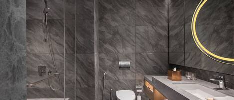 Une salle de bain moderne avec une douche en verre, des toilettes, un lavabo avec un miroir et des murs en marbre.