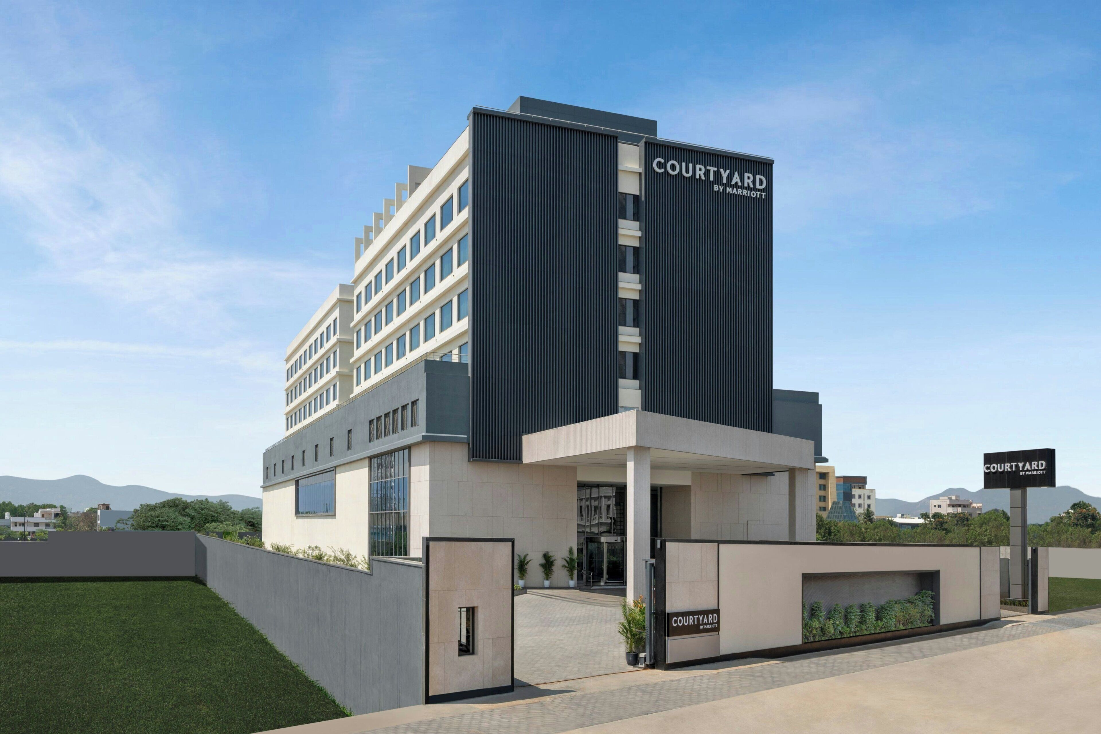 Ett Courtyard by Marriott-hotell med modern design, kännetecknat av en framträdande entré, ett platt tak och ett vackert anlagt område framför hotellet.