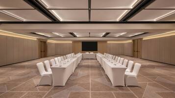 A conference room with a long table, white chairs, and a carpeted floor.