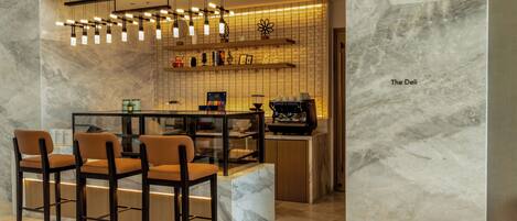 A modern bar area with marble walls, a glass partition, and multiple hanging light fixtures.