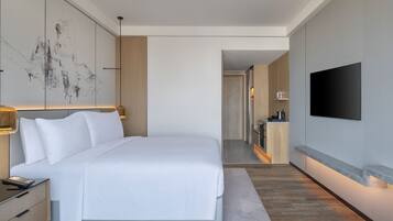 A modern hotel room with a large bed, bedside table, a mounted TV, and a wall-mounted artwork.