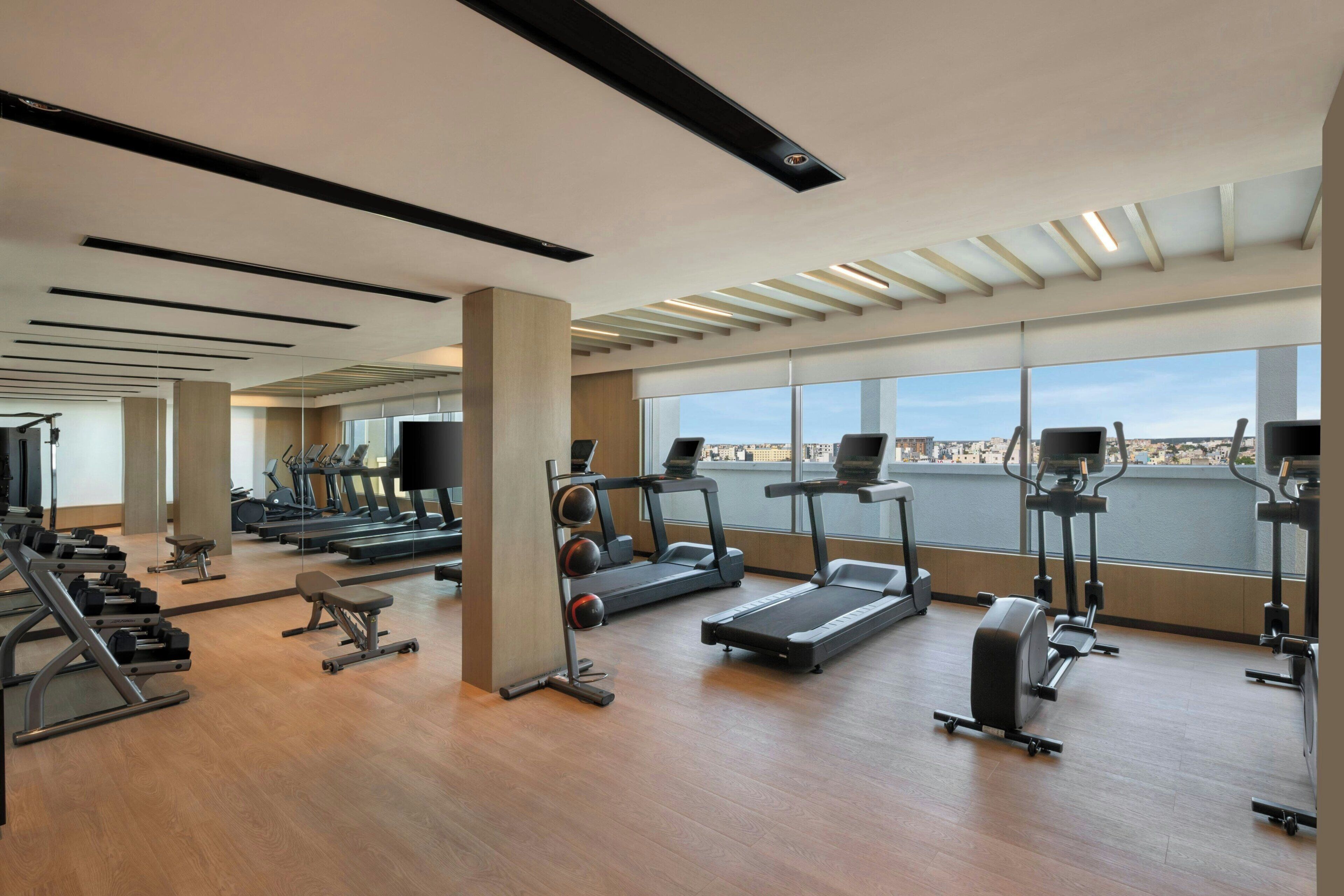 A gym with treadmills, elliptical machines, and weight stations.