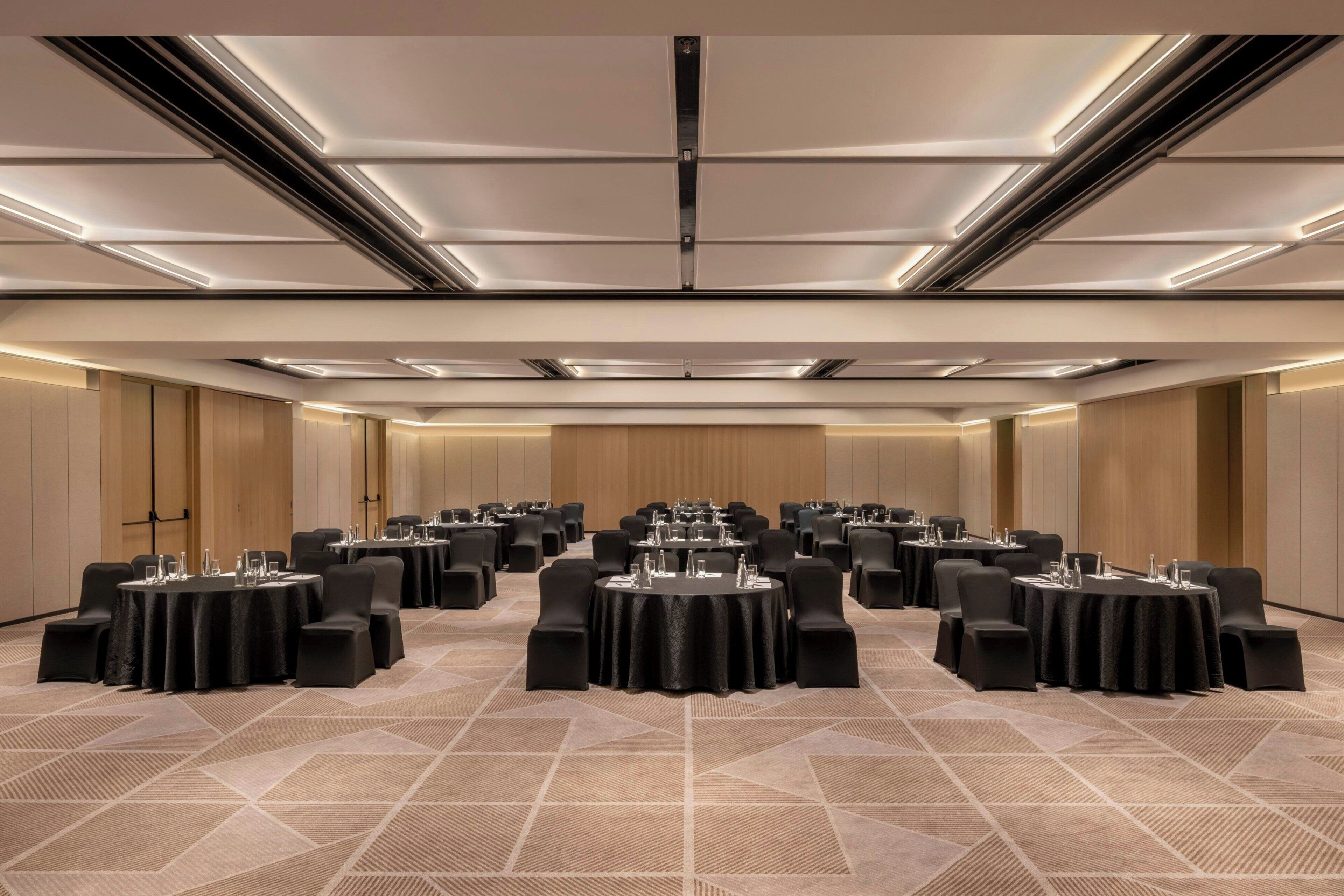 A conference room with multiple tables, chairs, and a carpeted floor.