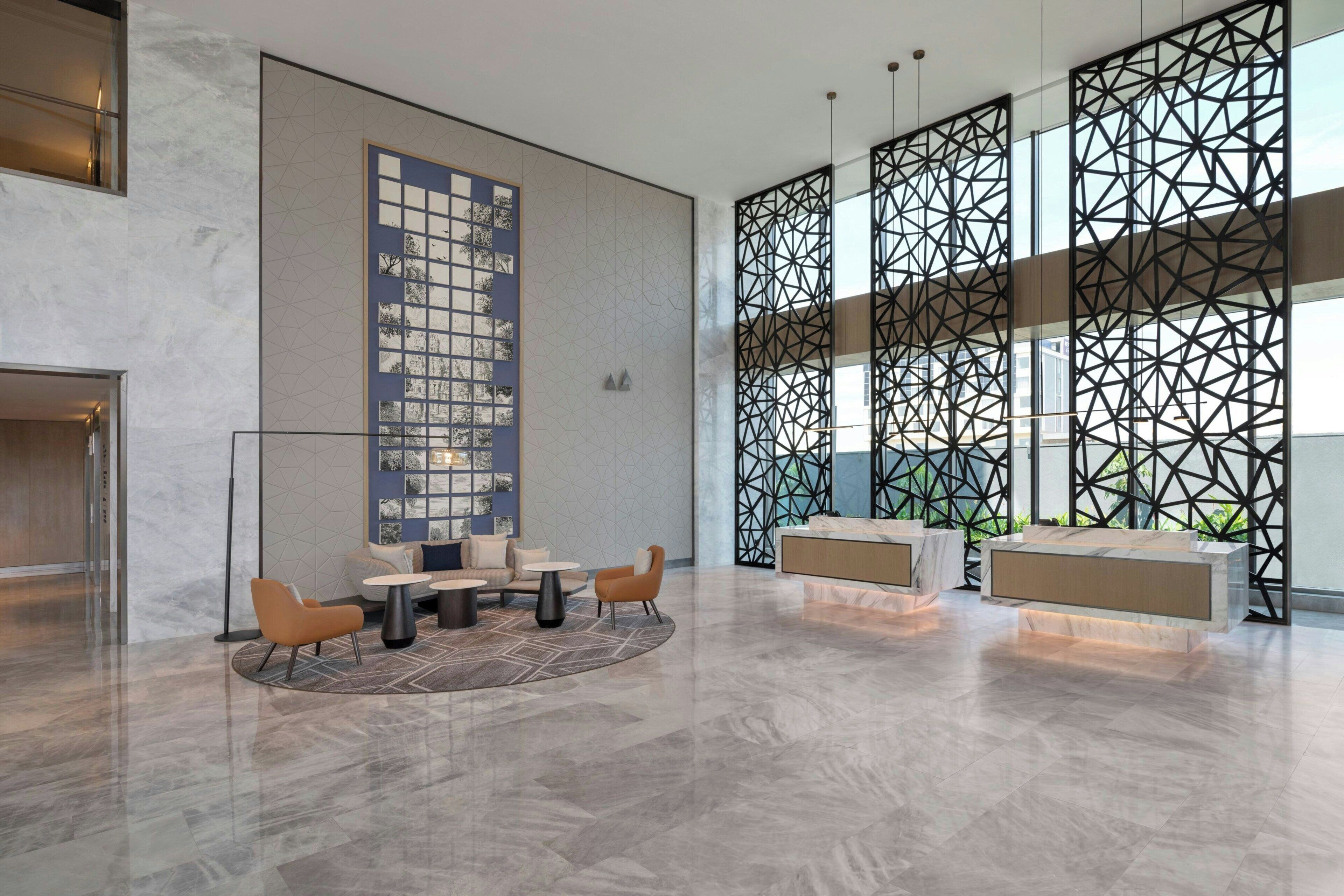 A spacious lobby with a reception desk, seating area, and decorative wall panels.