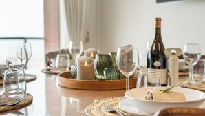 Una mesa de comedor dispuesta con copas de vino, platos y velas, lo que sugiere un espacio para comer.