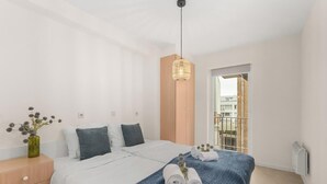 Un dormitorio moderno con cama, mesita de noche y lámpara colgante.