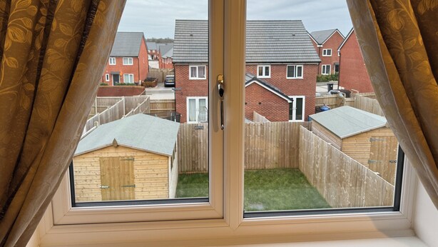 Una ventana con vista a una zona residencial, con casas y una cerca de madera.