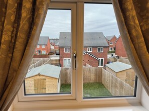 Una ventana con vista a una zona residencial, con casas y una cerca de madera.