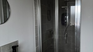 Un baño con lavamanos blanco, espejo y cabina de ducha de vidrio.