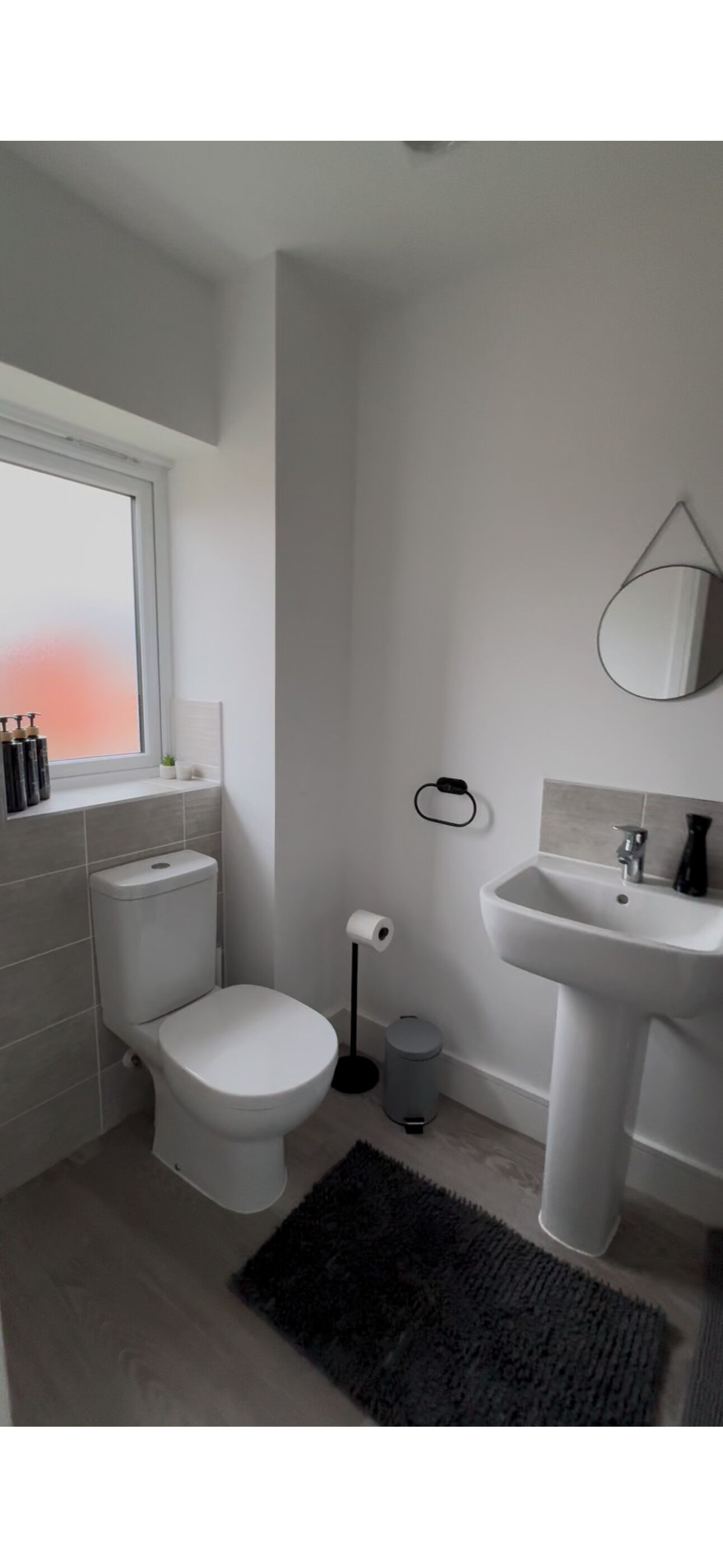 A modern bathroom with a toilet, sink, and window.