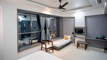 Habitación de hotel moderna con una ventana grande, una cama, una silla, una mesita y un televisor.