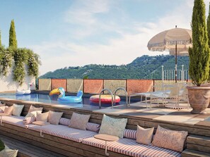 A pool area with lounge seating, a floating pool float, and a decorative umbrella. - Mama Shelter Lake Como (Como)
