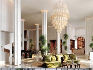 A spacious lobby with high ceilings, a large chandelier, and a green sofa. - Mama Shelter Lake Como (Como)