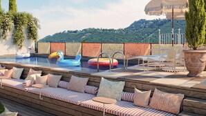 A pool area with lounge seating, a floating pool float, and a decorative umbrella. - Mama Shelter Lake Como (Como)