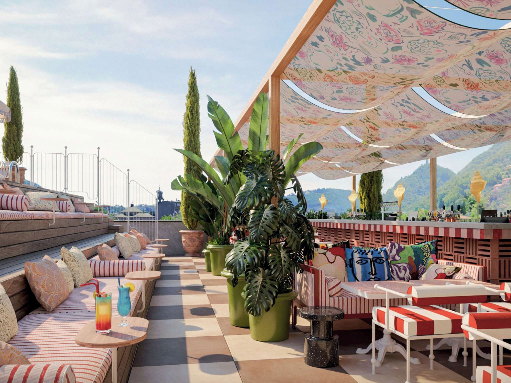 A rooftop bar with outdoor seating, potted plants, and a view of the cityscape.