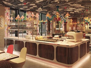 A restaurant with a bar area, a counter with food displays, and a seating area with chairs. - Mama Shelter Lake Como (Como)