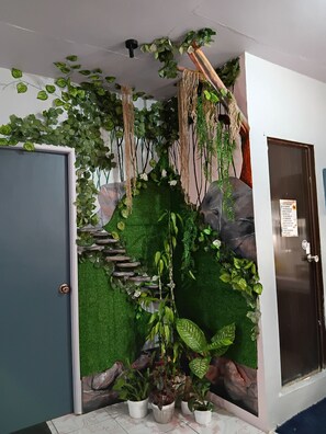A room with a green artificial wall, a staircase, and several potted plants. - Adorable 2-bedroom home in cool Baguio for your stay, with a  touch of Paris. (Baguio)