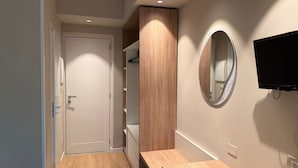 Une salle de bain moderne avec un meuble-lavabo en bois, un miroir et un téléviseur fixé au mur.