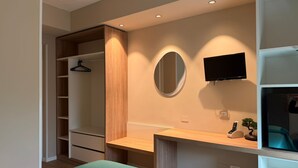 Une chambre à coucher comprenant un lit, une armoire, un miroir, une télévision et un bureau.