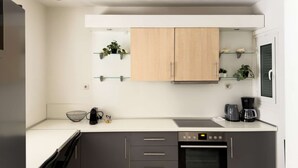 Eine moderne Küche mit grauen Schränken, einem eingebauten Backofen, einer Kaffeemaschine und einem Fenster mit Blick.