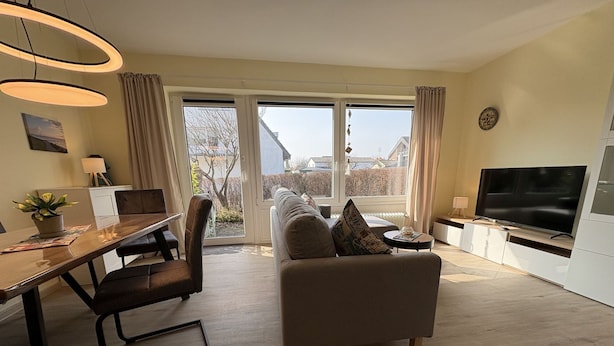 Een moderne woonkamer met een bank, een eettafel en een televisie.