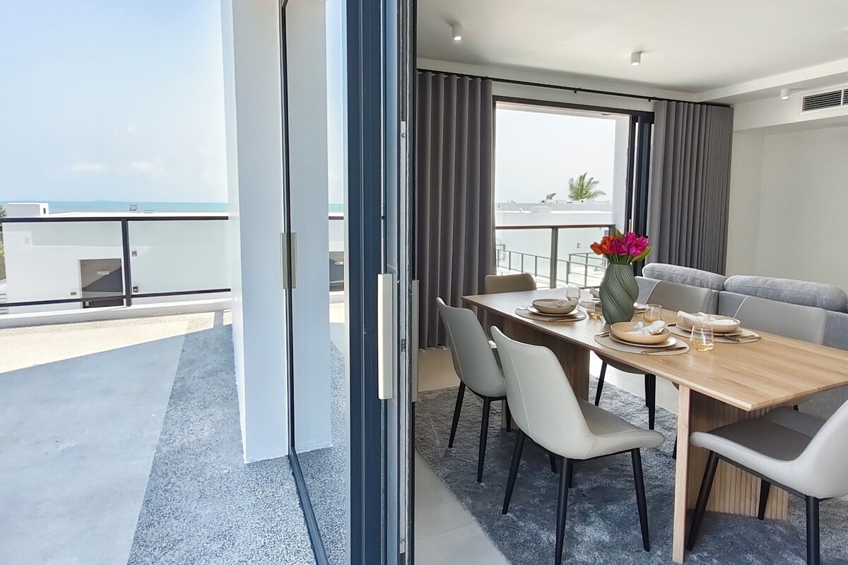 Una zona menjador moderna amb taula per a quatre, un sofà i vista al mar.