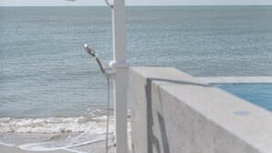 A concrete structure with a metal showerhead, a clear view of the ocean, and a beach in the background. - The Village Chumphon Hotel (Pathio)