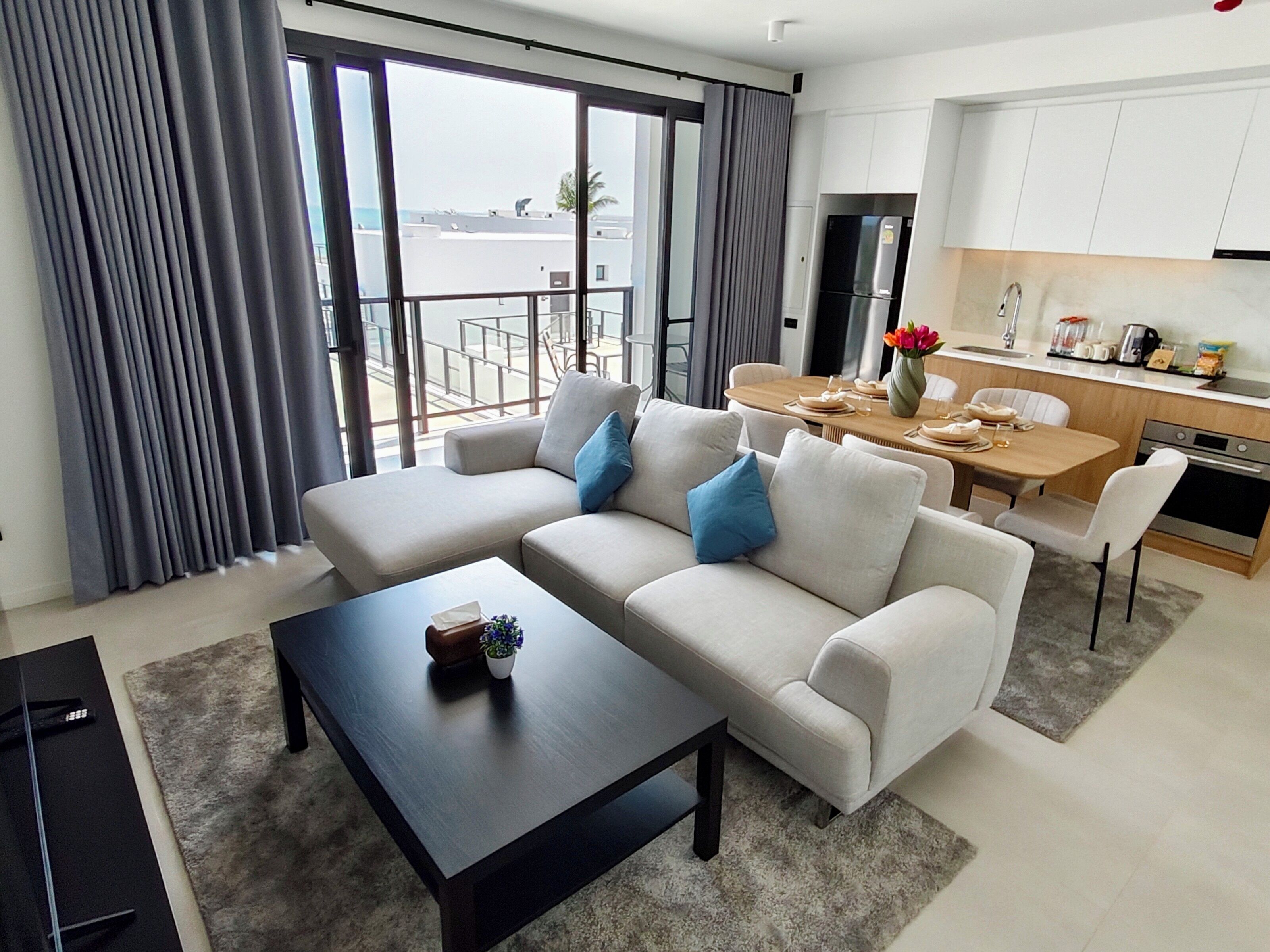 Een moderne woonkamer met een bank, salontafel en uitzicht op het balkon.