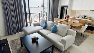 Een moderne woonkamer met een bank, salontafel en uitzicht op het balkon.