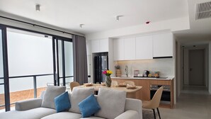 A modern living room with a sofa, coffee table, and dining area. - The Village Chumphon Hotel (Pathio)