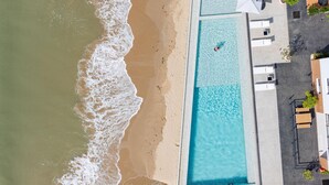 An aerial view of a beachside hotel with a swimming pool, beach, and adjacent buildings. - The Village Chumphon Hotel (Pathio)