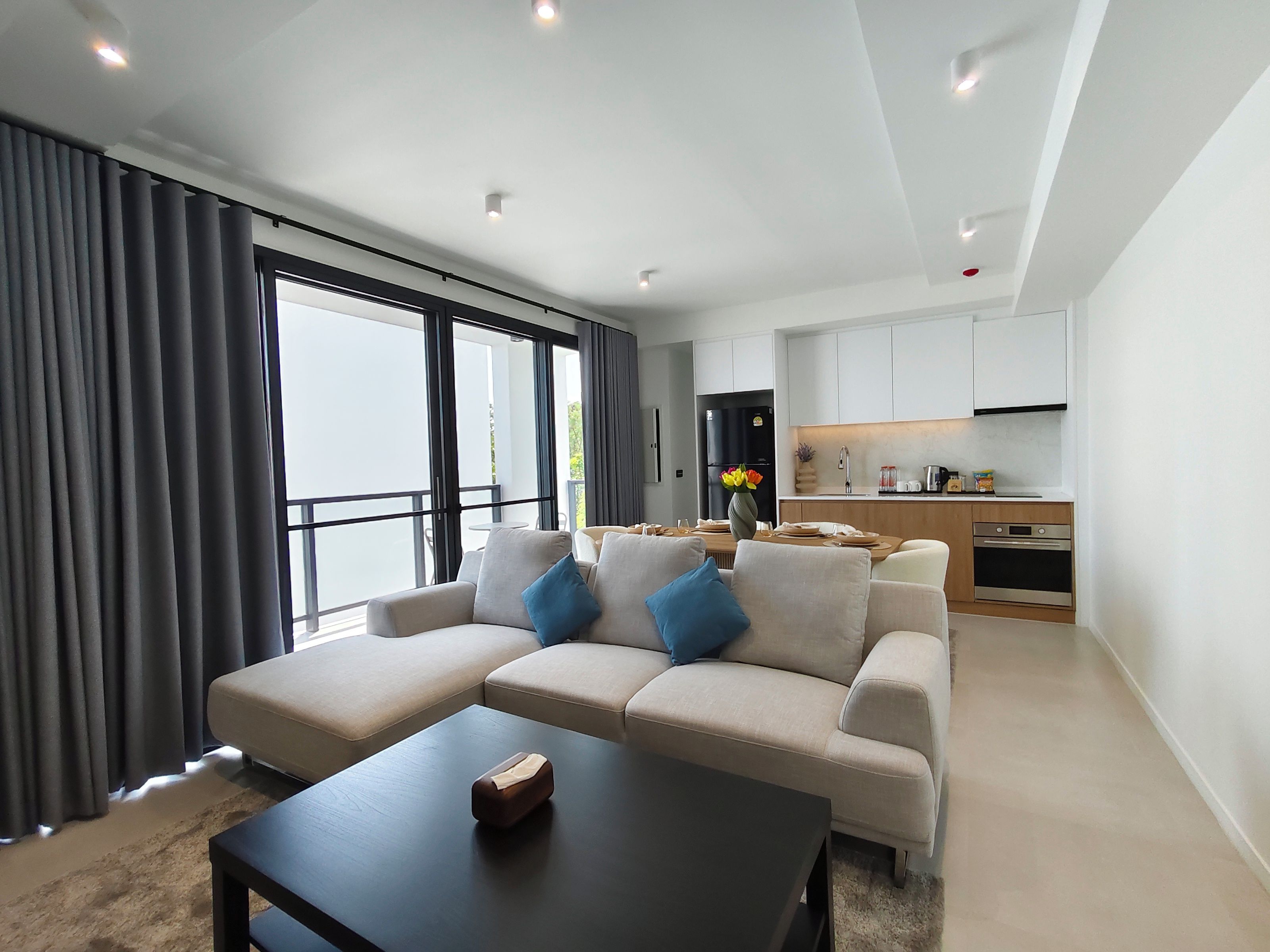 Una sala moderna con un sofá, una mesa de centro y vistas a la cocina.