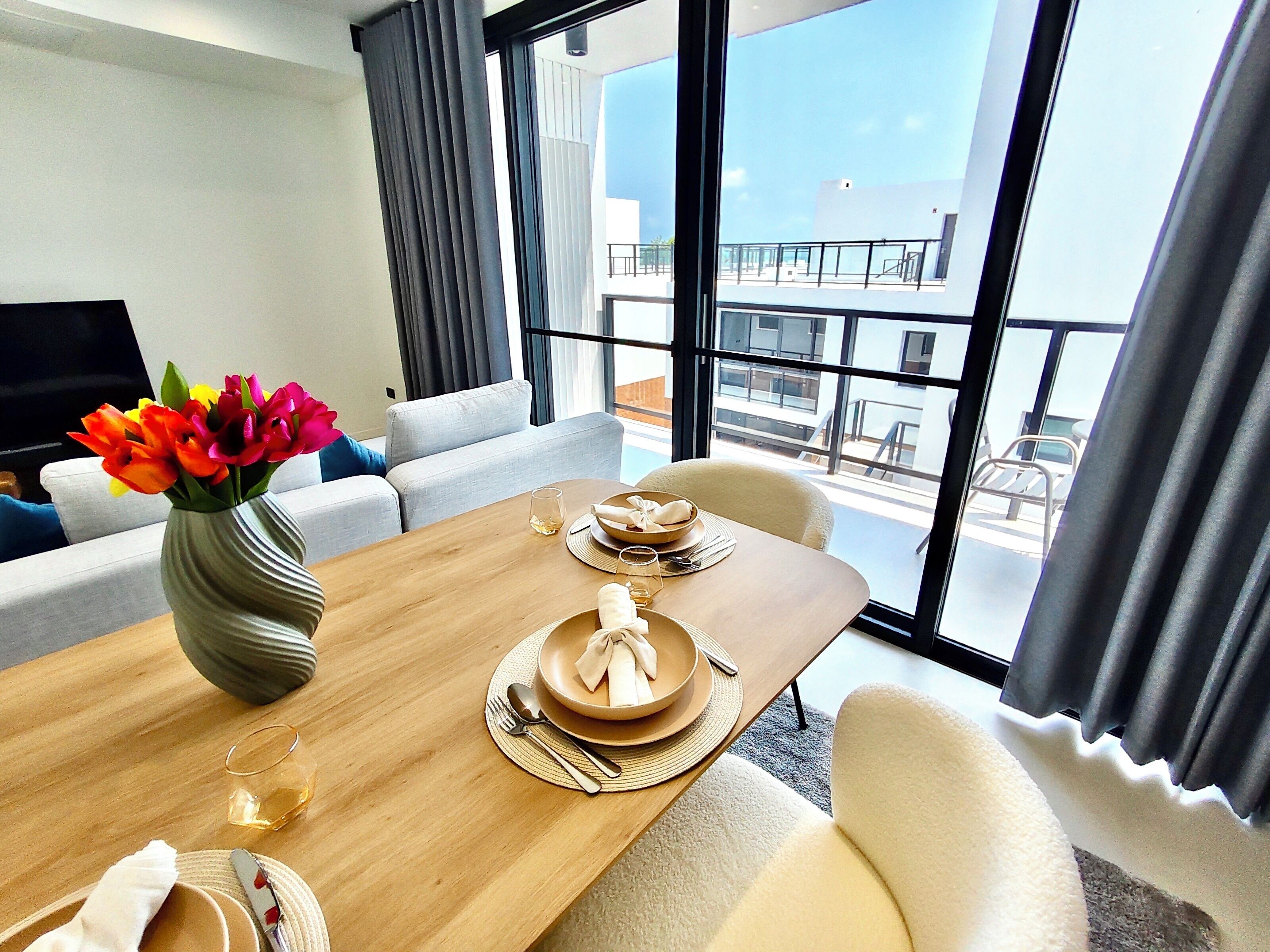 Une chambre d’hôtel moderne dotée d’un coin repas, d’un canapé, d’une télévision et offrant une vue sur la ville.