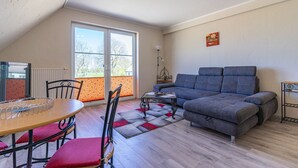 A living room with a sofa, a dining table with chairs, a radiator, and a window. - Pferdehof Königsstuhl - Apartment 1 Mecklenburger - Holidays at the riding stable - (Lohme)