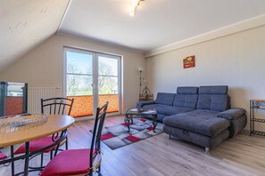 Una sala de estar con un sofá, una mesa de comedor con sillas, un radiador y una ventana.