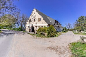 Un bâtiment à deux étages, doté d’un toit en pente, d’un escalier menant à l’étage supérieur et d’un chemin de terre qui aboutit à l’entrée.
