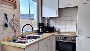 Una cocina moderna con un lavamanos de acero inoxidable, una cafetera y un horno empotrado.