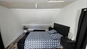 A bedroom with a bed, bedside tables, a nightstand, a heater, and a window. - ROOM FOR RENT IN A GUEST HOUSE (Navarrenx)