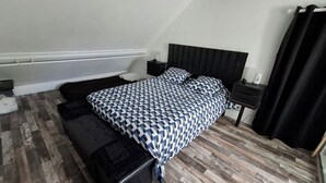 A bedroom with a bed, a bedside table, a nightstand, a bench, and a window with curtains. - ROOM FOR RENT IN A GUEST HOUSE (Navarrenx)