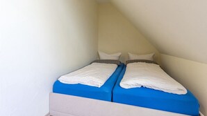 A small, single-room with two beds, a sloped ceiling, and plain walls. - Pferdehof Königsstuhl - Apartment 5 Friese - Holidays at the riding stable - Apartment (Lohme)