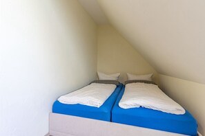 A small, single-room with two beds, a sloped ceiling, and plain walls. - Pferdehof Königsstuhl - Apartment 5 Friese - Holidays at the riding stable - Apartment (Lohme)
