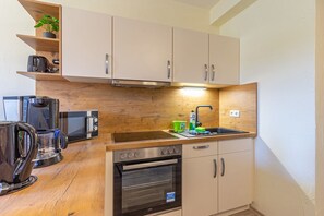 Een kleine keuken met een magnetron, broodrooster, waterkoker, spoelbak en oven.
