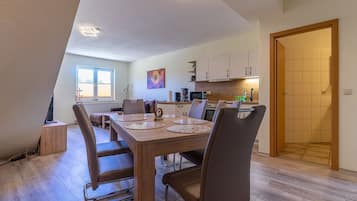 Un espace repas avec une table en bois, des chaises et une cuisine en arrière-plan.
