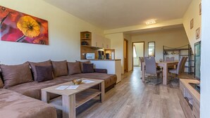 A living room with a sofa, a coffee table, and a dining area with a table and chairs. - Pferdehof Königsstuhl - Apartment 5 Friese - Holidays at the riding stable - Apartment (Lohme)