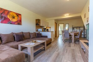 Een woonkamer met een bank, een salontafel en een eethoek met een tafel en stoelen.
